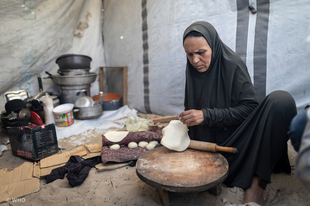 Une femme prépare du pain dans sa tente à Gaza.